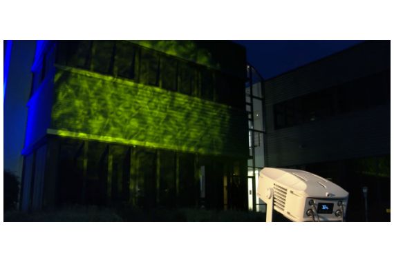 An Image of the Artecta projector, projecting an image onto the side of a building